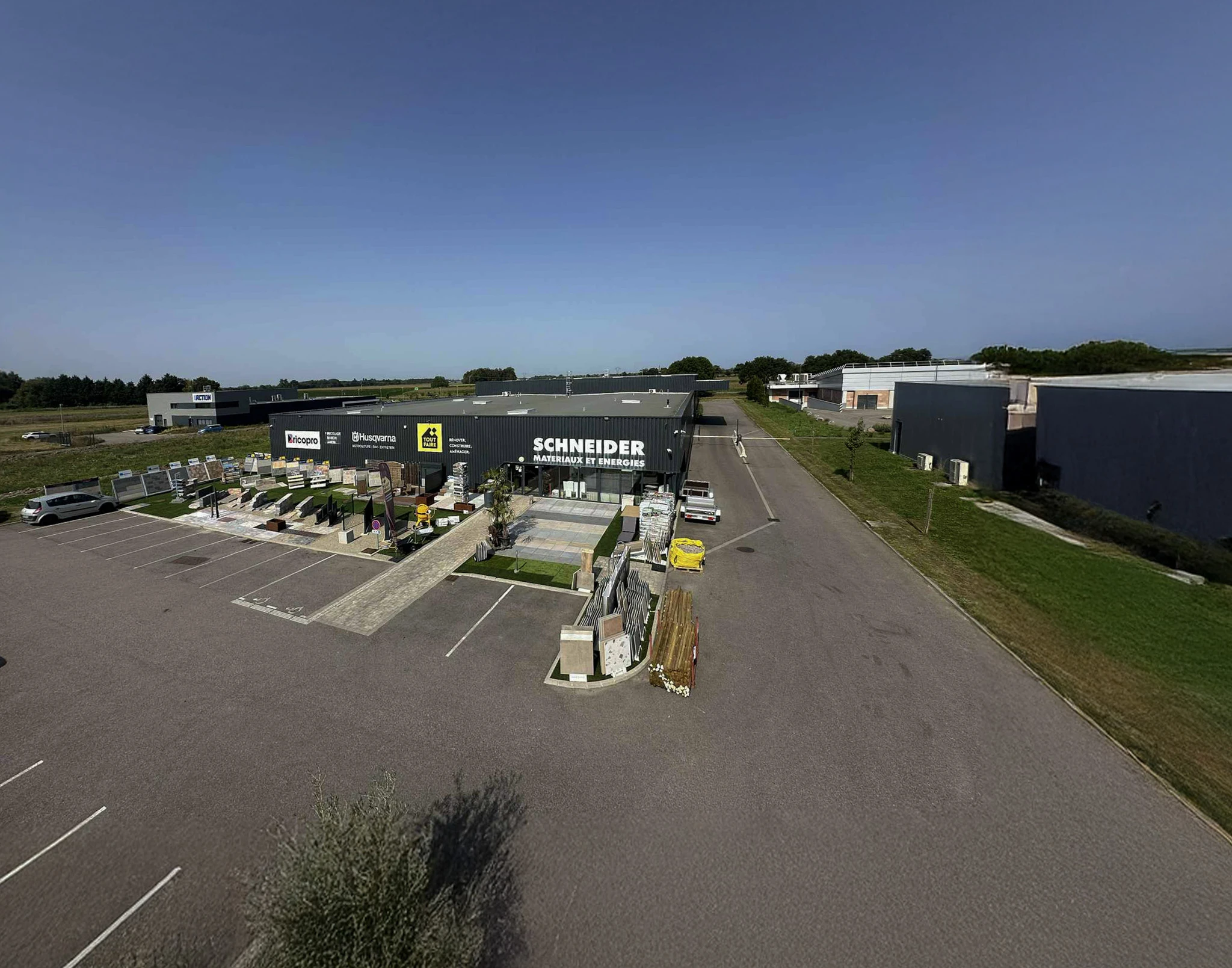 Vue a&eacute;rienne d'un complexe commercial de mat&eacute;riaux de construction avec magasin Schneider au centre