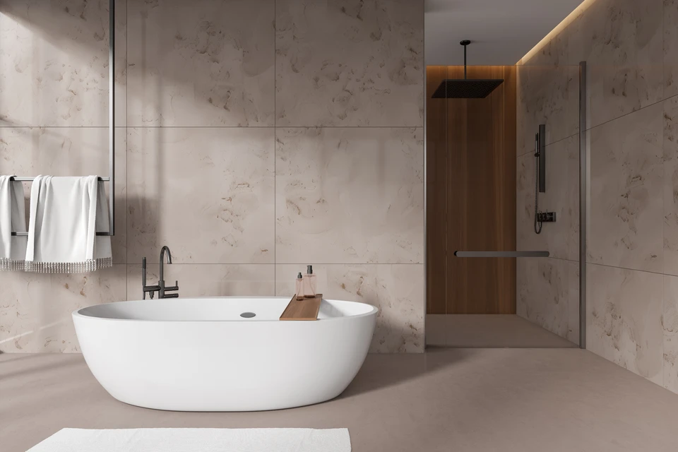 Salle de bain moderne avec baignoire îlot blanche ovale, mur en carrelage effet pierre gris anthracite, sèche-serviettes noir vertical