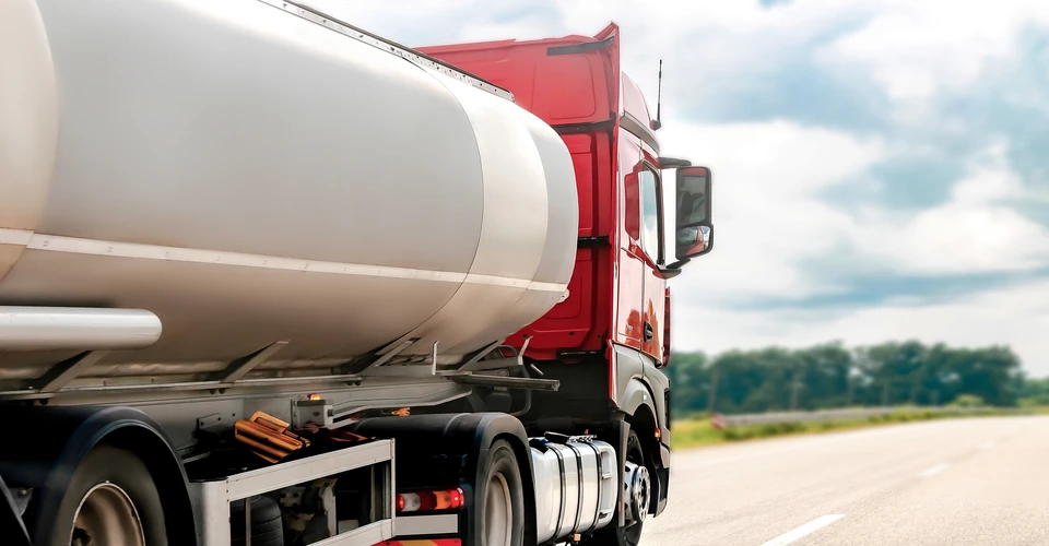 Camion-citerne blanc stationné sur route goudronnée sous ciel nuageux