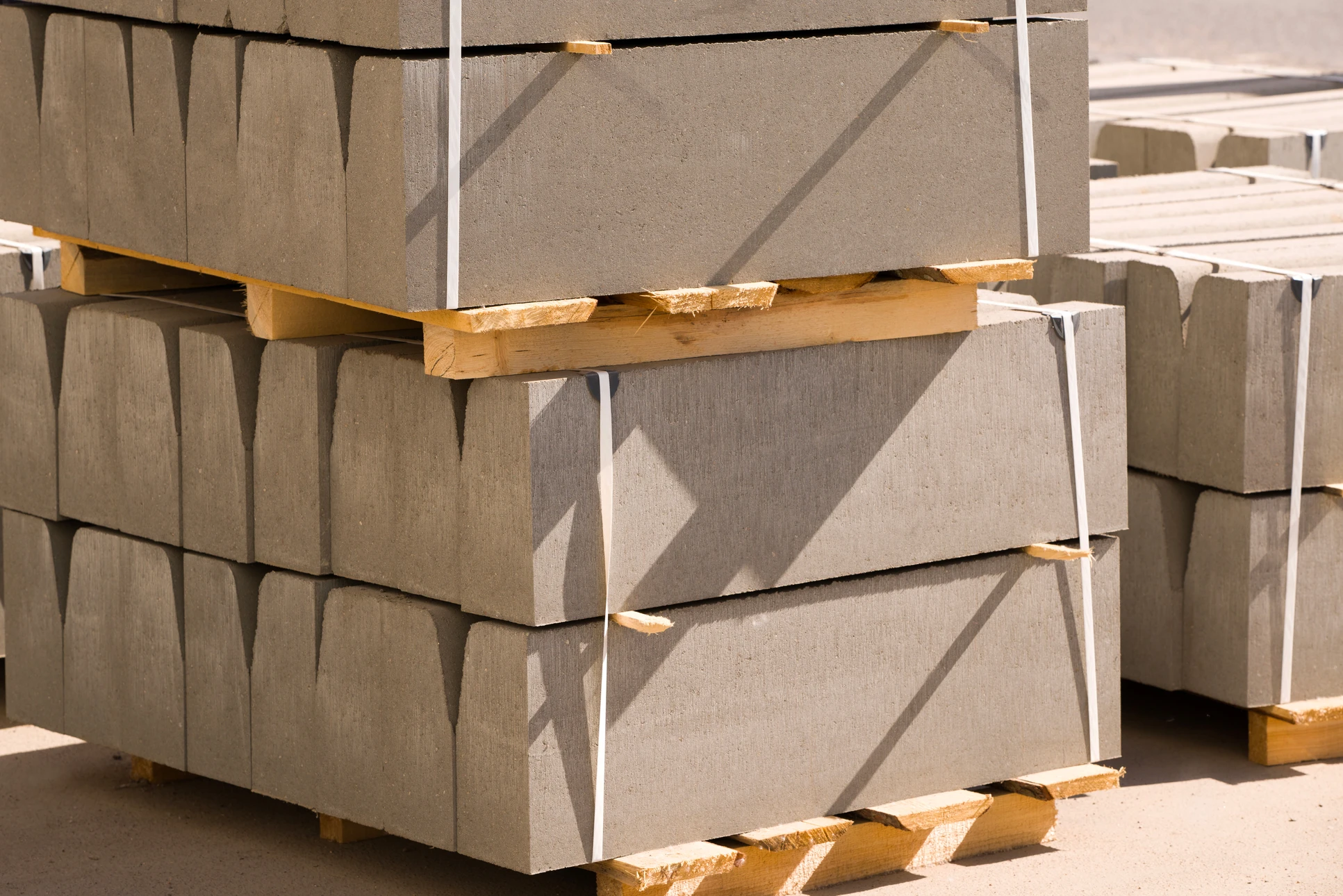 Livreur souriant en uniforme rouge avec casquette et gilet matelassé, faisant le geste du pouce levé des deux mains derrière un colis carton beige
